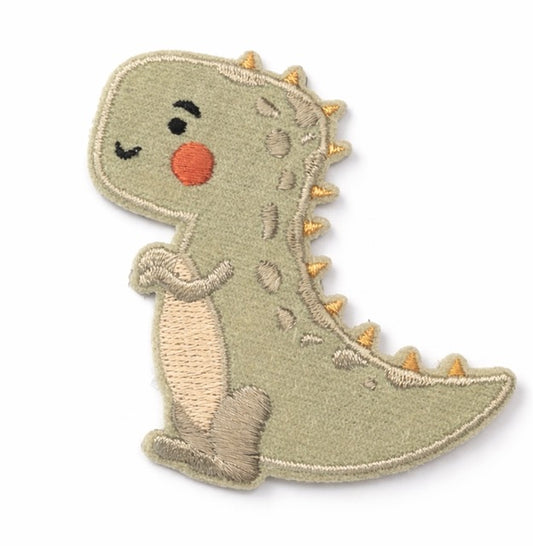 Bestickter T-Rex-Aufnäher aus Velours in Salbeigrün, sitzend, mit goldenen Rückenstacheln, kleinen Ärmchen, cremefarbenem Bauch und orangeroter Wange auf weißem Hintergrund. Größe 5x7cm, zum Aufbügeln oder Aufnähen.