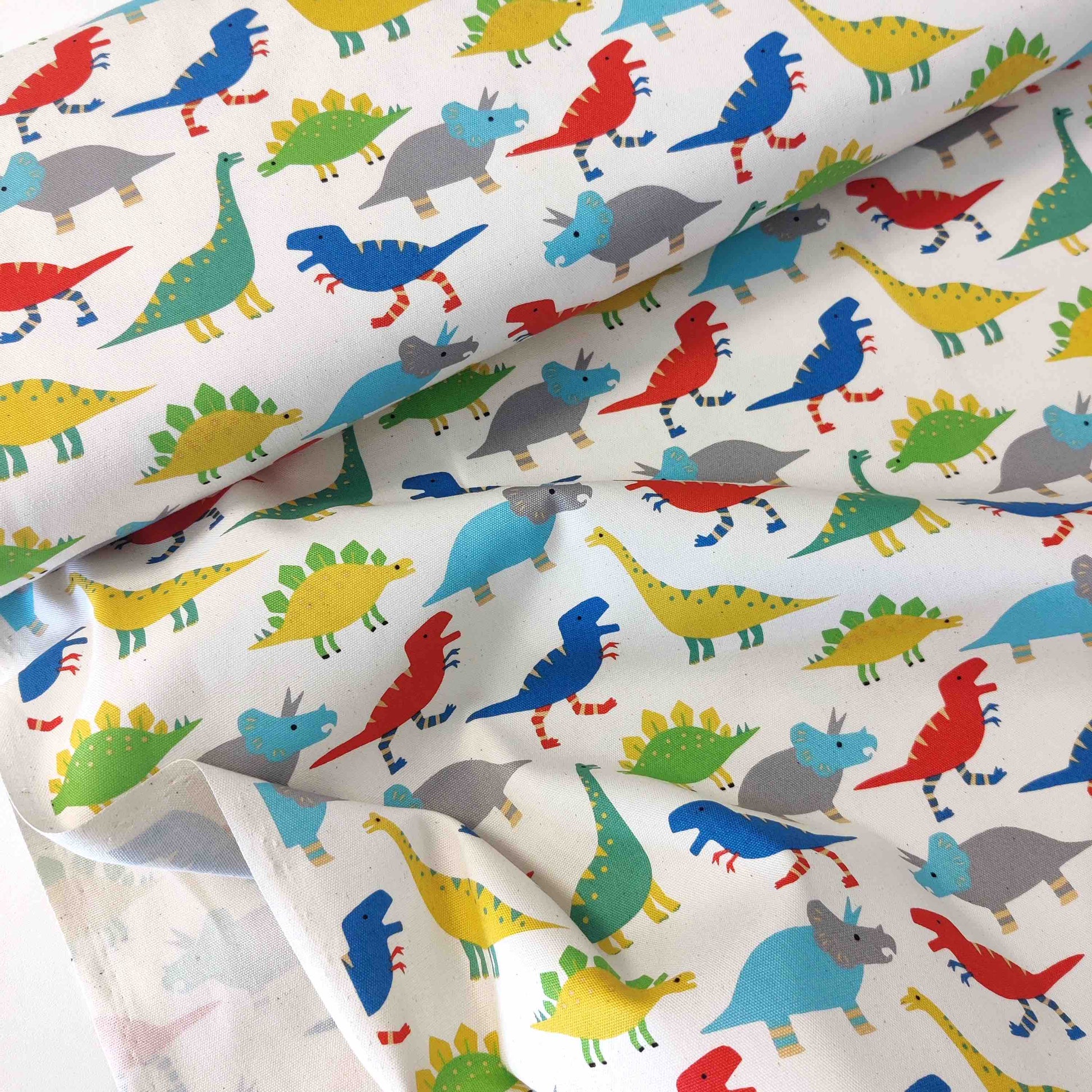 Japanischer Baumwollstoff von Sevenberry mit bunten Dinosauriern auf naturfarbenem Hintergrund.