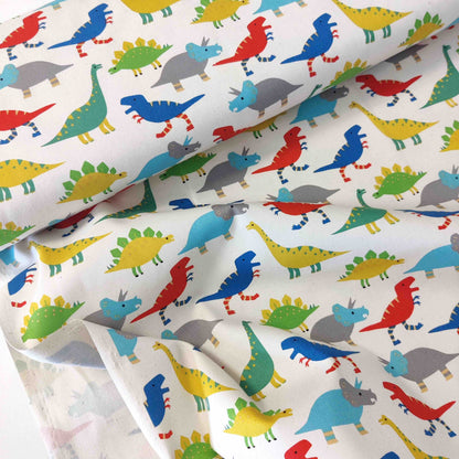 Japanischer Baumwollstoff von Sevenberry mit bunten Dinosauriern auf naturfarbenem Hintergrund.