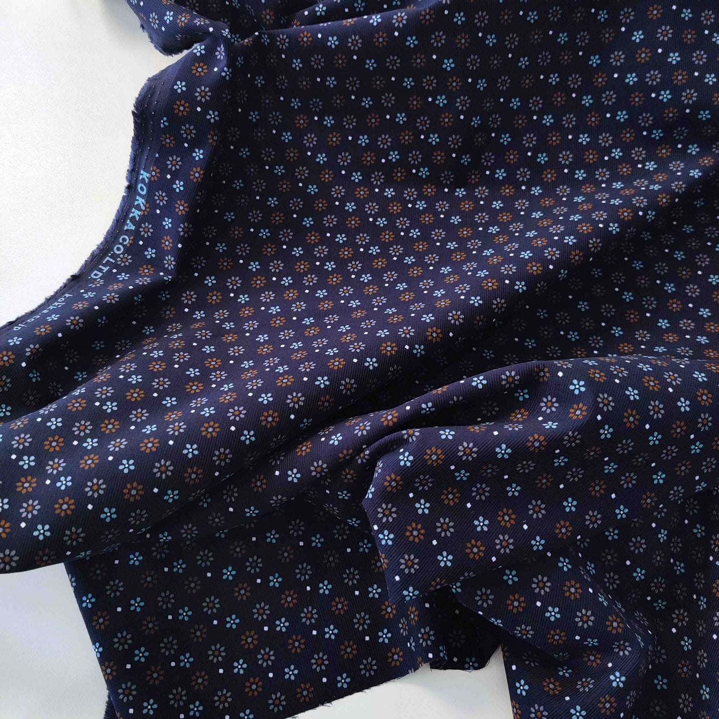Dunkelblauer Feincord von Kokka mit kleinen Blüten in Hellblau, Rost und Creme aus 100 % Baumwolle.