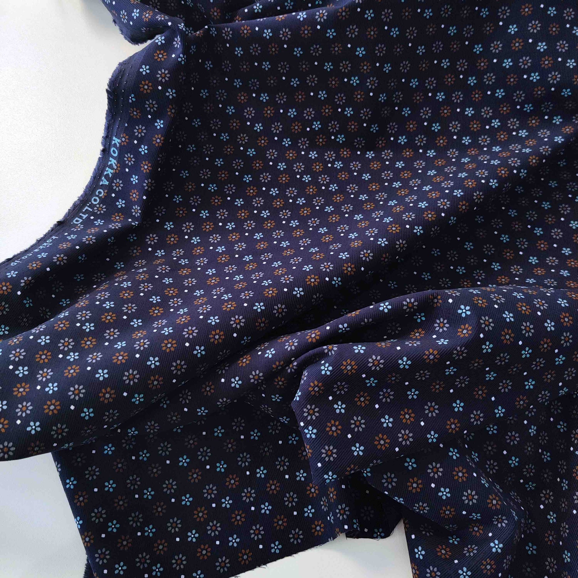 Dunkelblauer Feincord von Kokka mit kleinen Blüten in Hellblau, Rost und Creme aus 100 % Baumwolle.