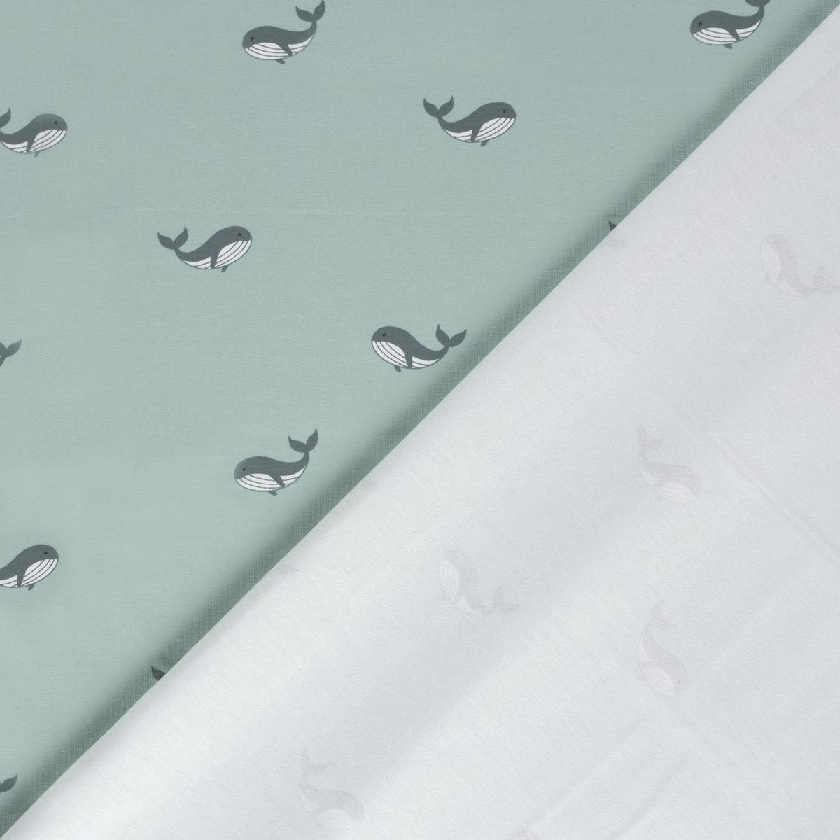 Vorder- und Rückseite des Stoffes: Baumwolljersey mit kleinen dunkelblaugrauen Walen auf einem grünlich wirkenden hellen Grund.