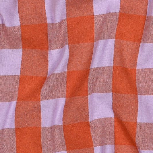 Der Stoff zeigt ein großzügiges Karomuster in leuchtendem Terrakotta und zartem Flieder. An den Kreuzungspunkten entstehen durch die Garngärbung natürliche Mischtöne in einem warmen Rosa-Terrakotta. Die Webstruktur ist gleichmäßig und fest, der Griff weich und angenehm. Das Muster wirkt mutig, modern und zeitlos zugleich.