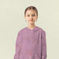 Kind trägt einen altrosafarbenen Pullover aus Sweat mit feinem Sprenkelmuster.