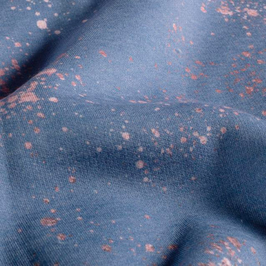 Nahaufnahme mit Stofffalten: Sweat mit unregelmäßigen hellen und dunkleren Sprenkeln auf gedeckt blauem Grund.